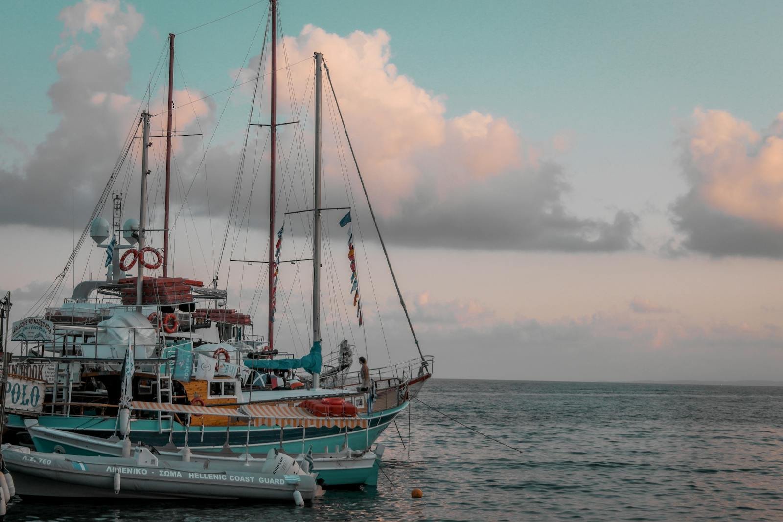 A vibrant sailing ship moored at the coast under calm skies, creating a serene maritime scene.