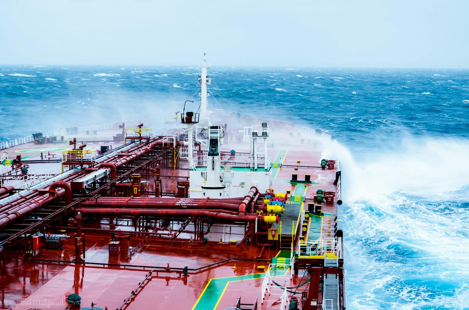 A cargo ship navigating through rough ocean waves on a bright day.
